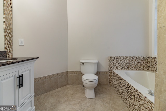 bathroom featuring tile patterned floors, vanity, a relaxing tiled tub, and toilet