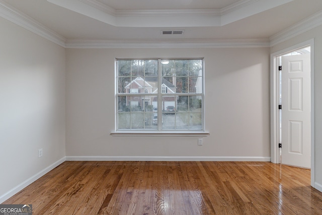 unfurnished room with wood-type flooring, a raised ceiling, and crown molding