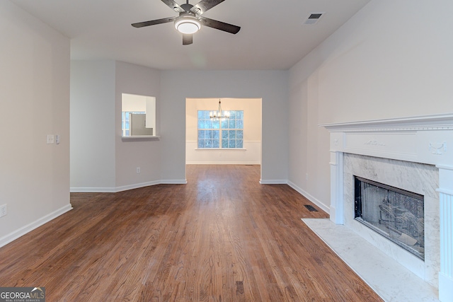 unfurnished living room featuring ceiling fan with notable chandelier, wood-type flooring, and a fireplace