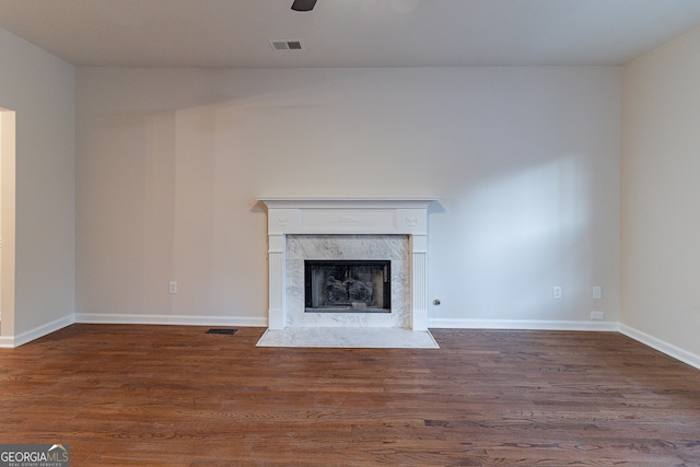 unfurnished living room featuring ceiling fan, a high end fireplace, and dark wood-type flooring