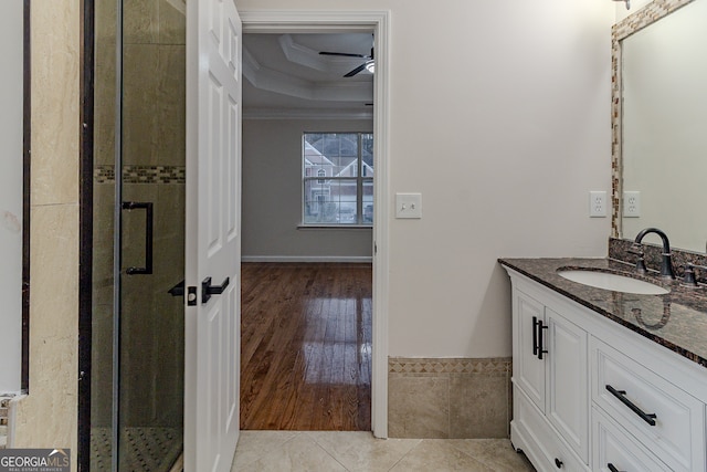 bathroom featuring ceiling fan, crown molding, hardwood / wood-style floors, a shower with door, and vanity