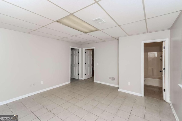 unfurnished room with a drop ceiling and light tile patterned floors