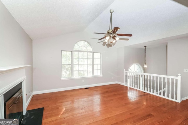 unfurnished living room with hardwood / wood-style floors, ceiling fan, lofted ceiling, and a textured ceiling