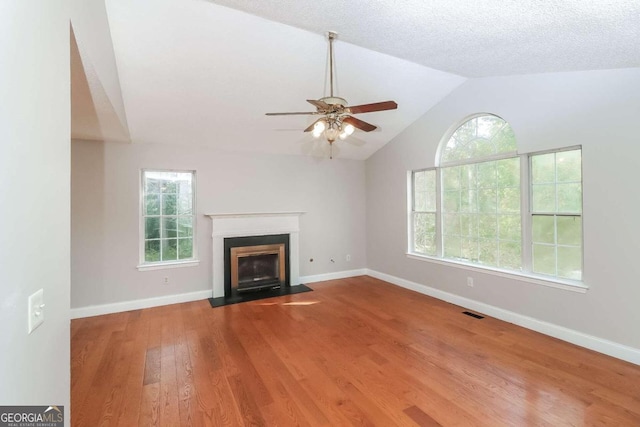 unfurnished living room with hardwood / wood-style flooring, ceiling fan, a healthy amount of sunlight, and vaulted ceiling