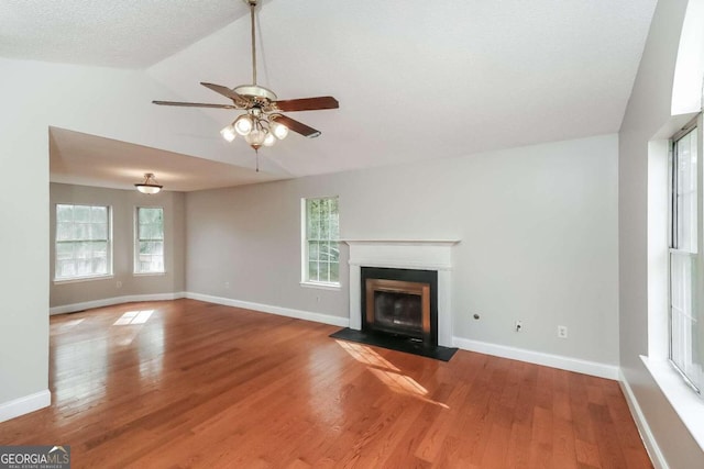 unfurnished living room featuring hardwood / wood-style flooring, ceiling fan, a healthy amount of sunlight, and lofted ceiling