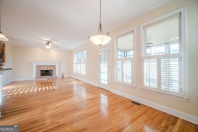 unfurnished living room featuring light hardwood / wood-style floors, ceiling fan, and crown molding