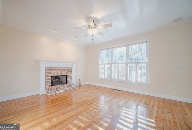 unfurnished living room featuring light hardwood / wood-style floors, a brick fireplace, ceiling fan, and ornamental molding