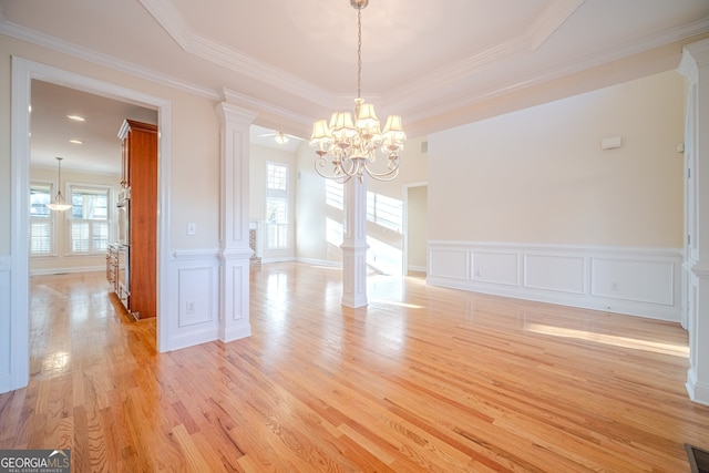 spare room featuring plenty of natural light, a raised ceiling, ornamental molding, and light hardwood / wood-style flooring