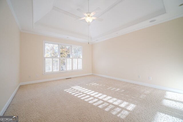 empty room featuring carpet floors, a raised ceiling, ceiling fan, and crown molding