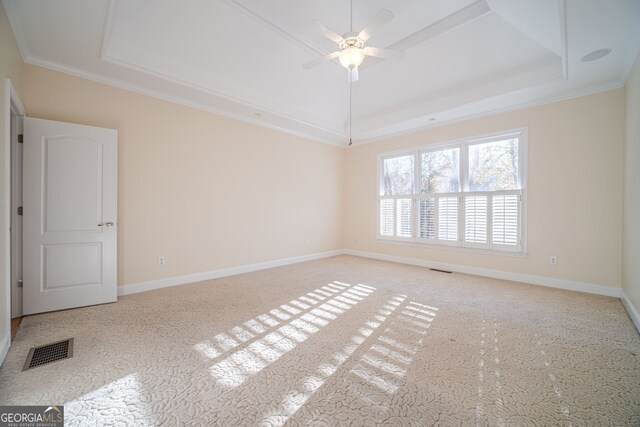 unfurnished room with ceiling fan, a raised ceiling, light colored carpet, and crown molding