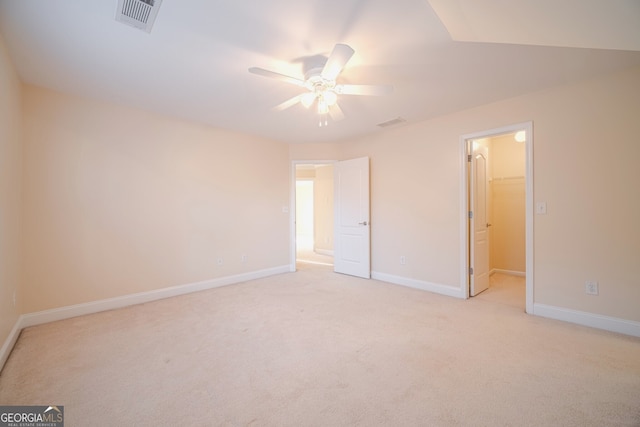 unfurnished bedroom with a closet, a spacious closet, ceiling fan, and light colored carpet