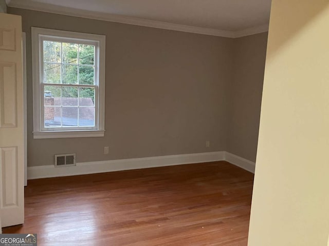 empty room with crown molding and light hardwood / wood-style flooring