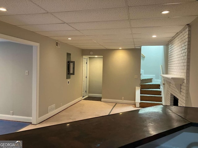 basement featuring a fireplace, electric panel, and a drop ceiling