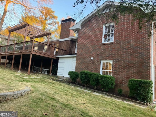 rear view of property featuring a pergola, a lawn, and a wooden deck