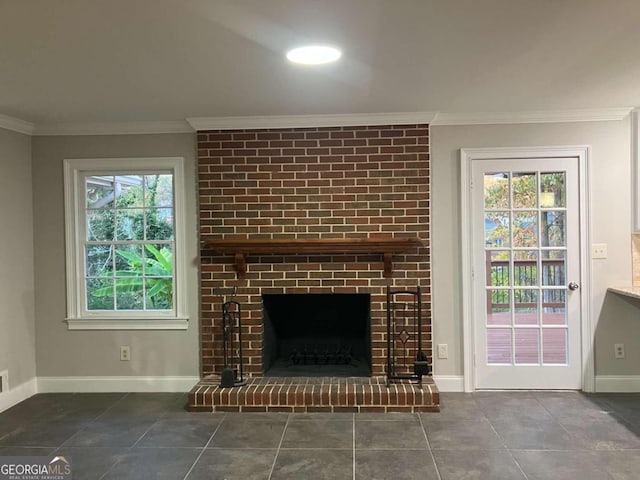 unfurnished living room featuring dark tile patterned floors, crown molding, a wealth of natural light, and a brick fireplace