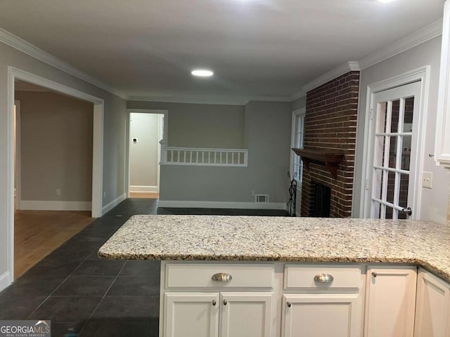 kitchen featuring dark wood-type flooring, light stone counters, crown molding, a fireplace, and white cabinets