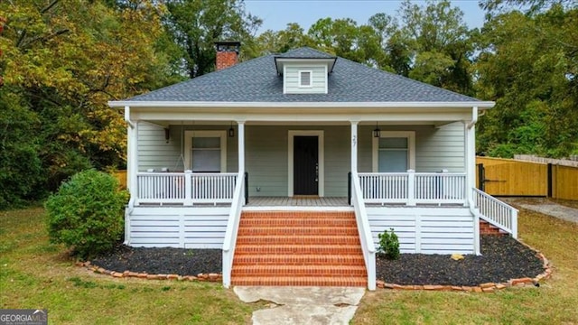 bungalow-style house featuring a porch, fence, stairs, roof with shingles, and a chimney