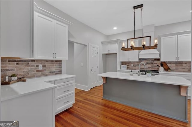 kitchen with backsplash, white cabinetry, pendant lighting, and light hardwood / wood-style floors