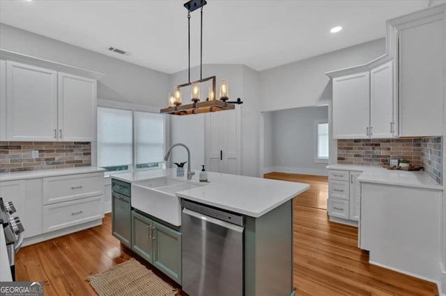 kitchen featuring a sink, stainless steel appliances, light countertops, light wood-type flooring, and backsplash