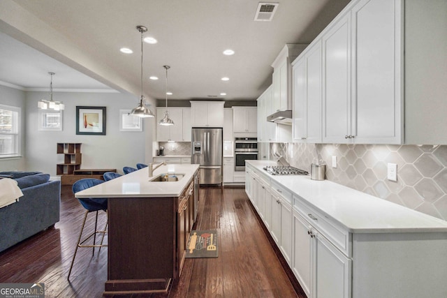 kitchen featuring pendant lighting, a center island with sink, dark hardwood / wood-style floors, white cabinetry, and stainless steel appliances