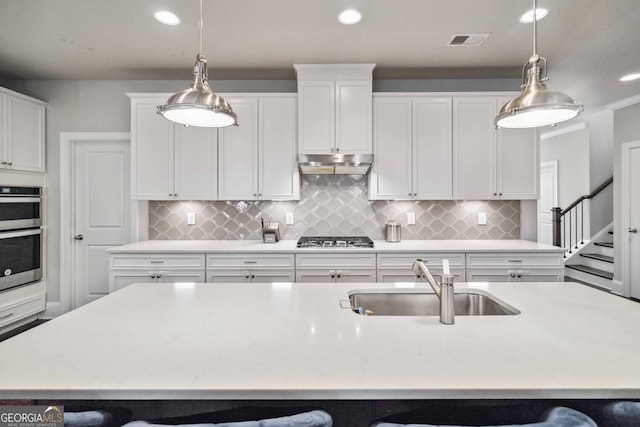 kitchen featuring a center island with sink, sink, hanging light fixtures, and a breakfast bar area