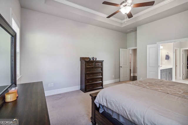 bedroom featuring connected bathroom, ceiling fan, a tray ceiling, light carpet, and ornamental molding