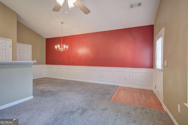 unfurnished room featuring ceiling fan with notable chandelier, carpet floors, and vaulted ceiling