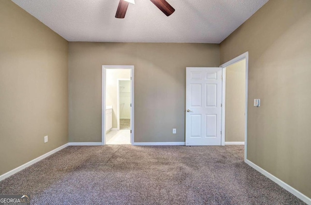 unfurnished bedroom featuring ceiling fan, light colored carpet, ensuite bathroom, and a textured ceiling