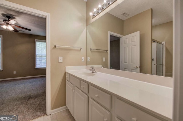 bathroom featuring vanity, a textured ceiling, ceiling fan, and a shower with shower door