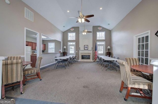 carpeted dining room with high vaulted ceiling and ceiling fan