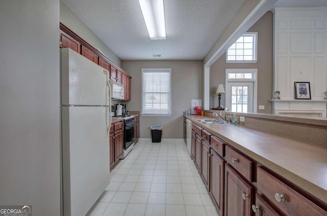 kitchen featuring a textured ceiling, white appliances, a wealth of natural light, and sink