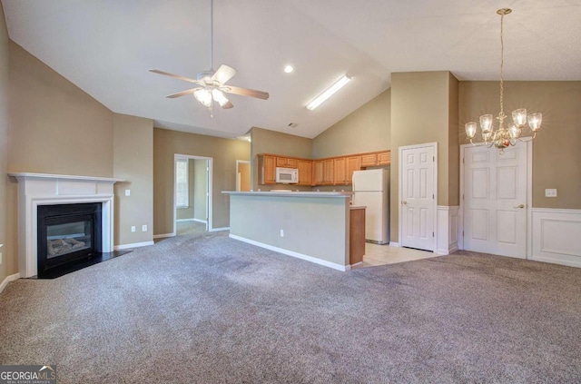 unfurnished living room with light carpet, high vaulted ceiling, and ceiling fan with notable chandelier