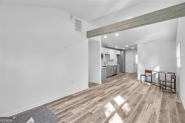 living room featuring light hardwood / wood-style floors, vaulted ceiling, and sink