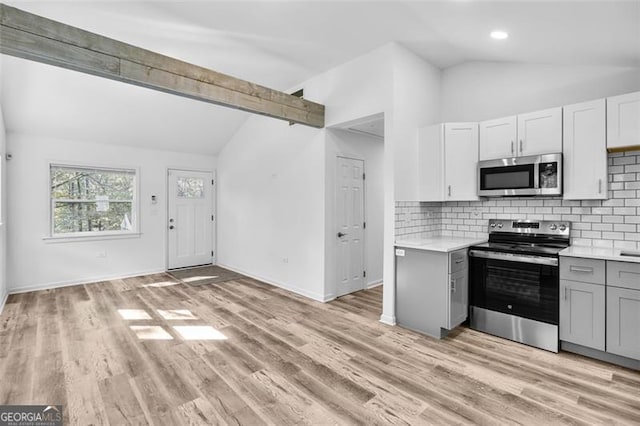 kitchen featuring tasteful backsplash, light hardwood / wood-style flooring, lofted ceiling with beams, and appliances with stainless steel finishes