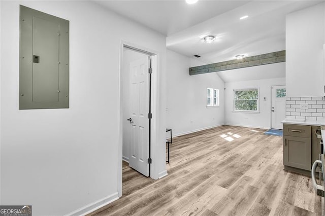 interior space with electric panel, lofted ceiling with beams, and light wood-type flooring