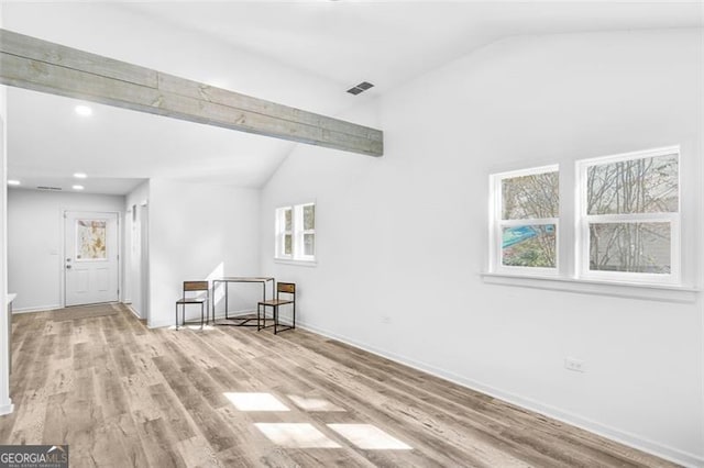 empty room with vaulted ceiling with beams, plenty of natural light, and light wood-type flooring