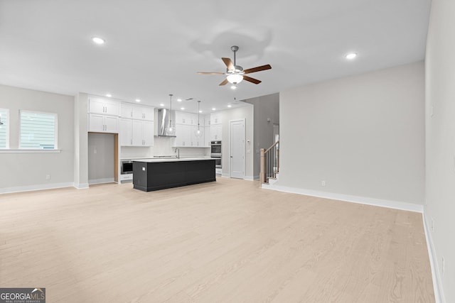 unfurnished living room with sink, ceiling fan, and light hardwood / wood-style flooring