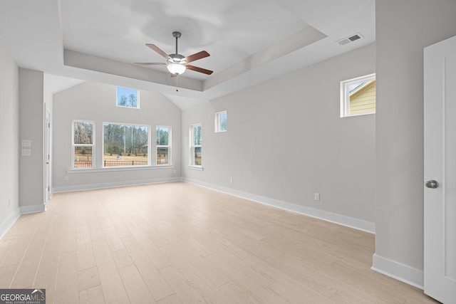 empty room featuring ceiling fan, a tray ceiling, and light hardwood / wood-style floors