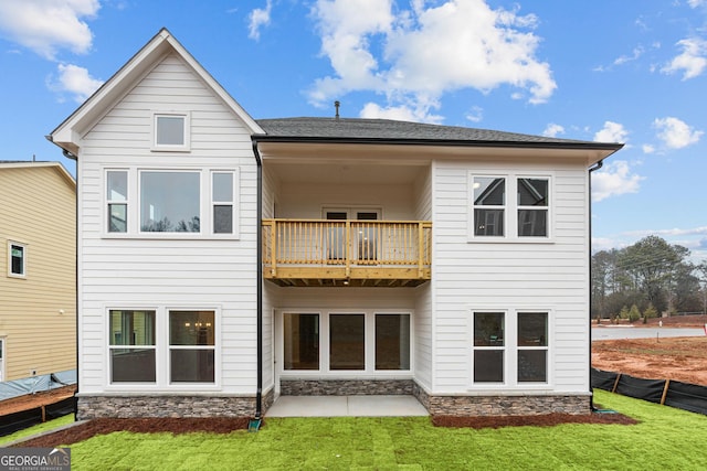 back of house with a balcony, a patio area, and a lawn