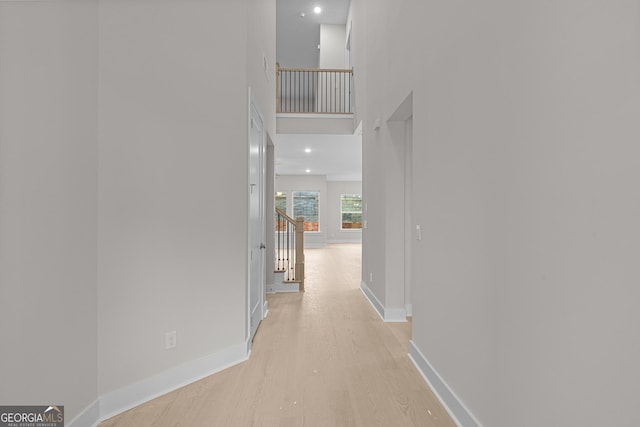 hallway with a high ceiling and light wood-type flooring