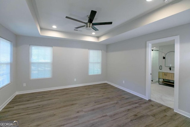 unfurnished room with hardwood / wood-style floors, a tray ceiling, and ceiling fan