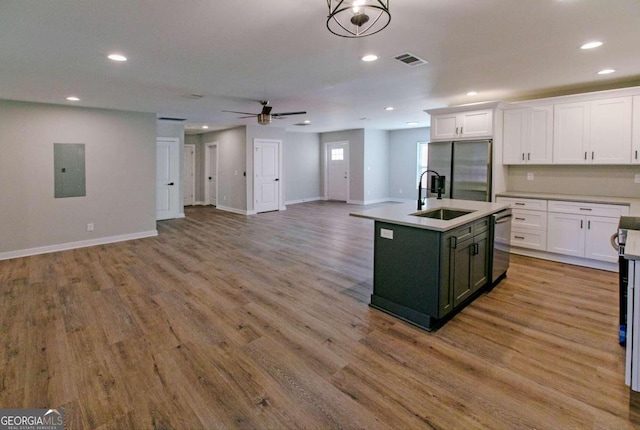 kitchen with ceiling fan with notable chandelier, sink, light wood-type flooring, an island with sink, and appliances with stainless steel finishes