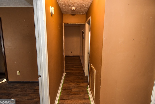 hallway with dark hardwood / wood-style floors and a textured ceiling