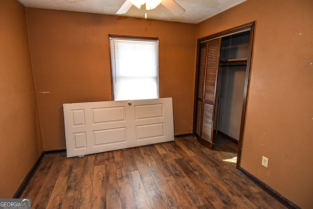 unfurnished bedroom featuring a textured ceiling, ceiling fan, dark wood-type flooring, and a closet