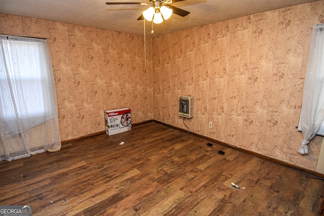 unfurnished room with dark hardwood / wood-style floors, ceiling fan, and heating unit