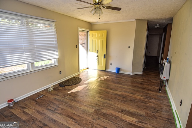 empty room featuring dark hardwood / wood-style floors, ceiling fan, a textured ceiling, and heating unit