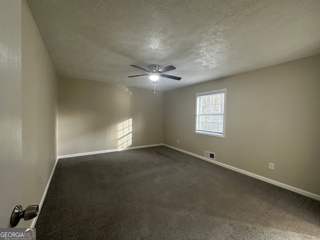 empty room with ceiling fan, dark carpet, and a textured ceiling