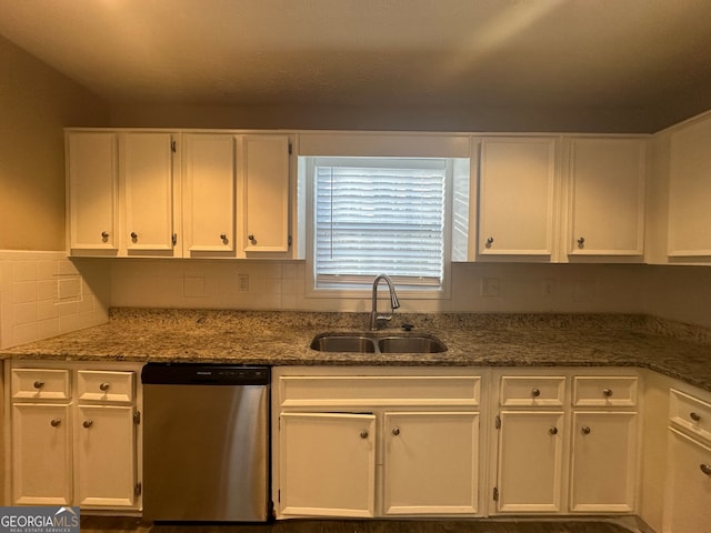 kitchen featuring decorative backsplash, stainless steel dishwasher, sink, dark stone countertops, and white cabinetry