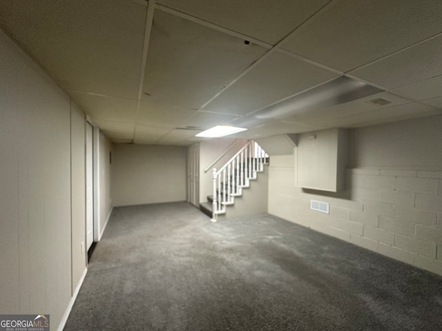 basement with a paneled ceiling and carpet