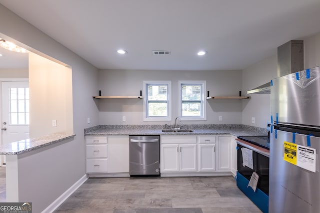 kitchen with white cabinets, sink, light hardwood / wood-style flooring, light stone counters, and stainless steel appliances